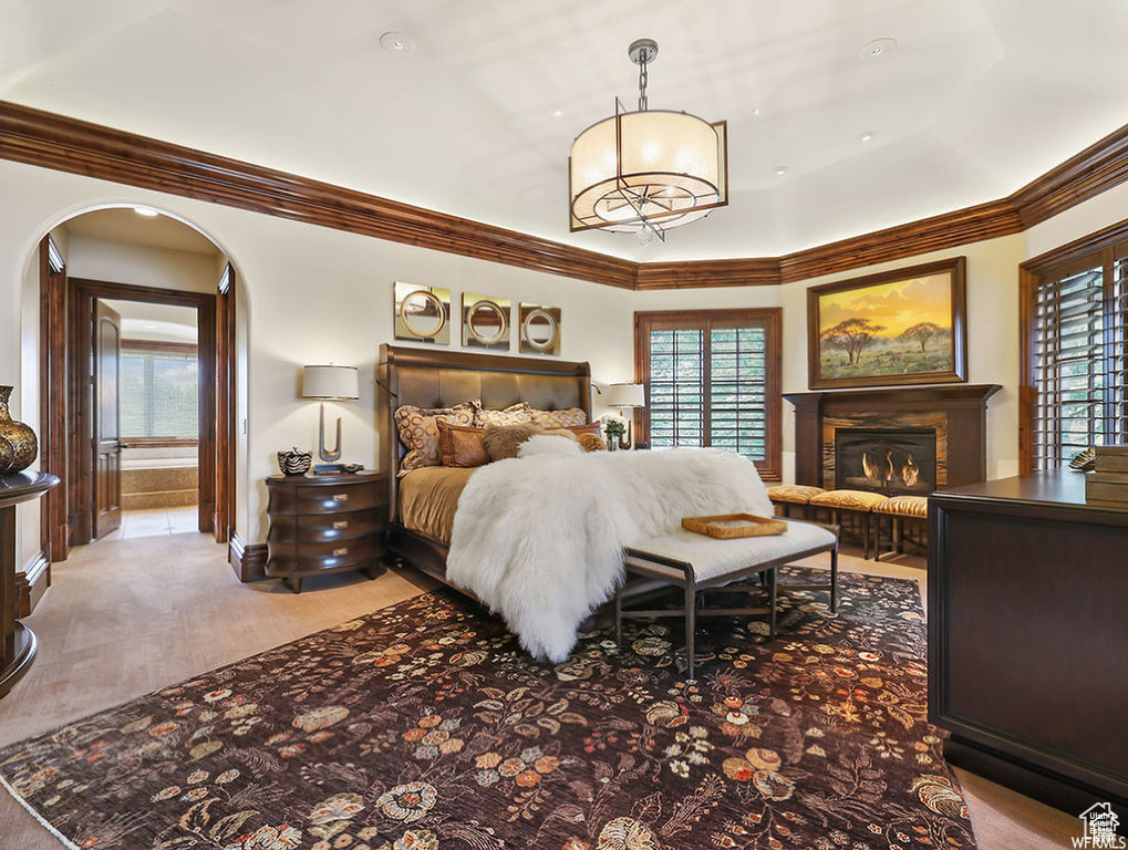 Bedroom featuring arched walkways, a glass covered fireplace, and crown molding