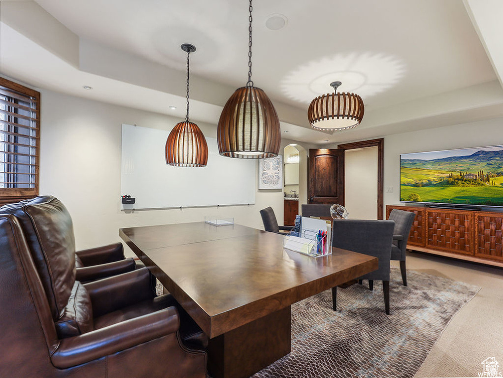 Carpeted home office featuring arched walkways, recessed lighting, and a raised ceiling