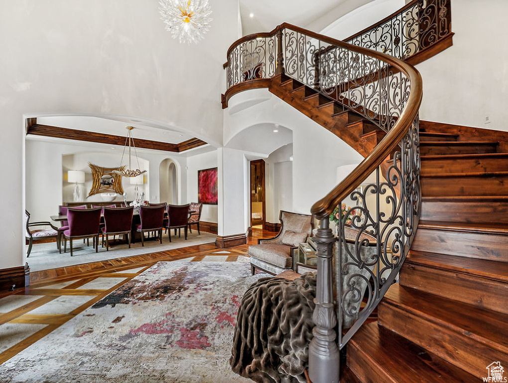 Stairway with baseboards, a high ceiling, and arched walkways