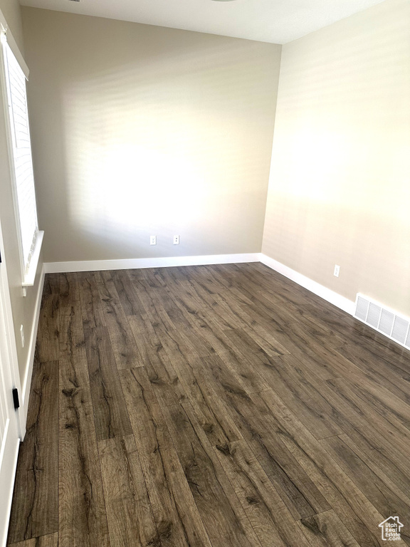 Unfurnished room featuring dark wood-type flooring, baseboards, and plenty of natural light