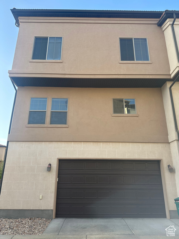 Back of house with a garage and stucco siding