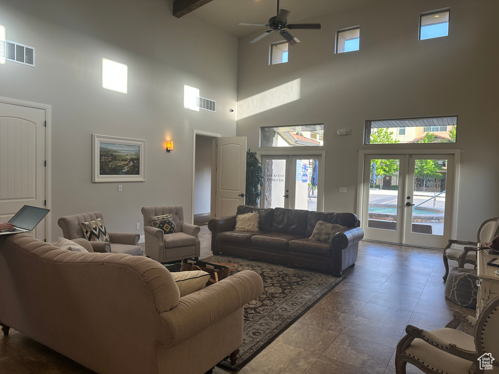 Living room with a high ceiling, ceiling fan, and french doors