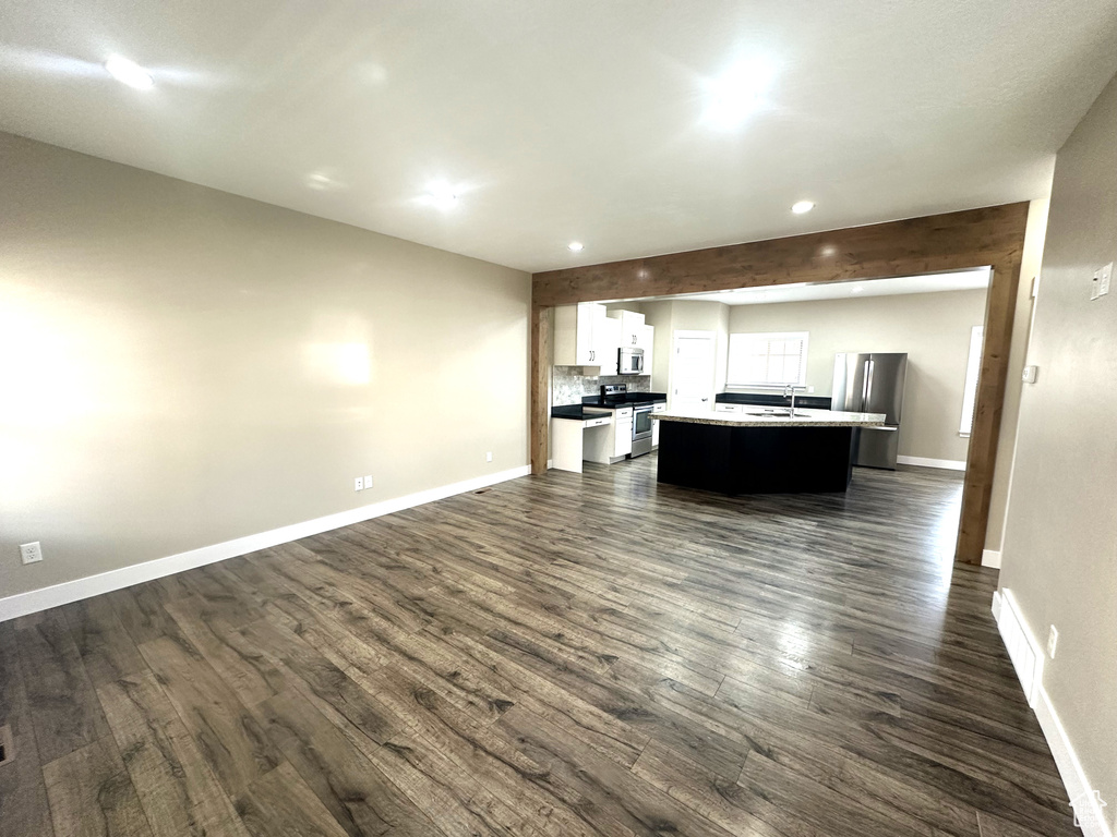 Living room featuring dark wood-style flooring, baseboards, and recessed lighting