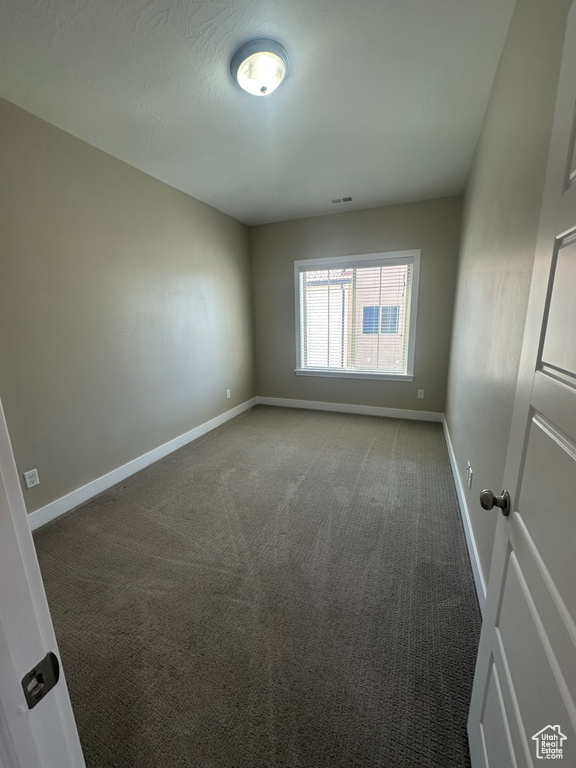 Carpeted spare room featuring baseboards