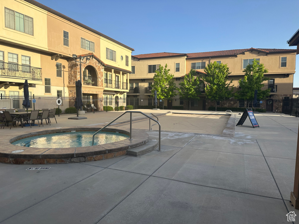 View of swimming pool with a hot tub and fence