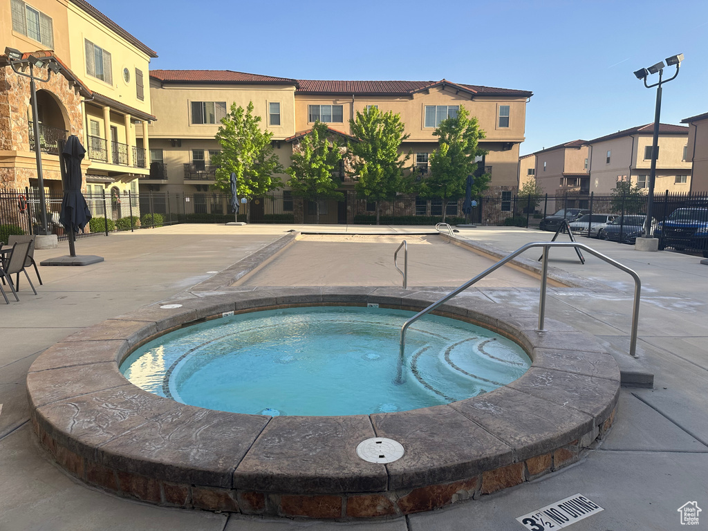 View of pool with fence, a community hot tub, and a residential view