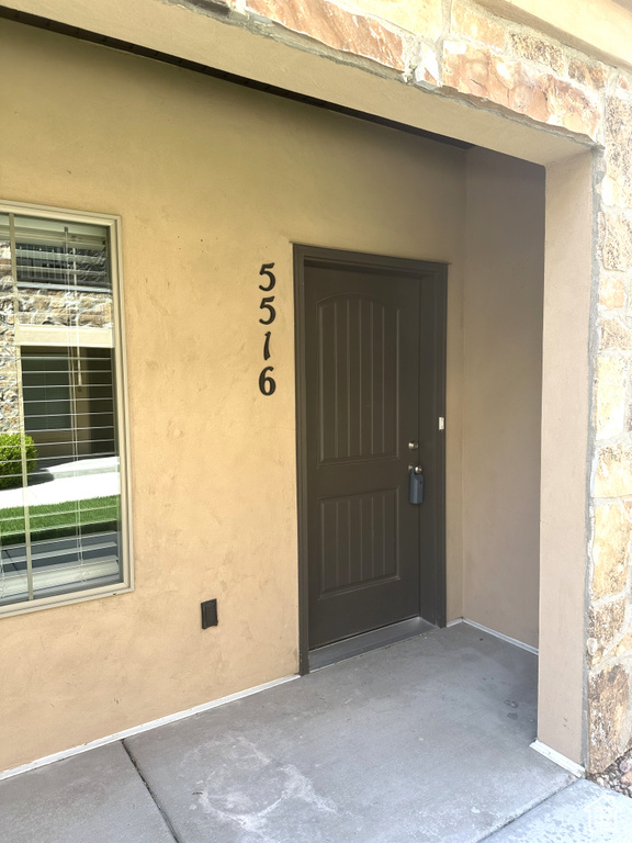 Entrance to property with stone siding and stucco siding