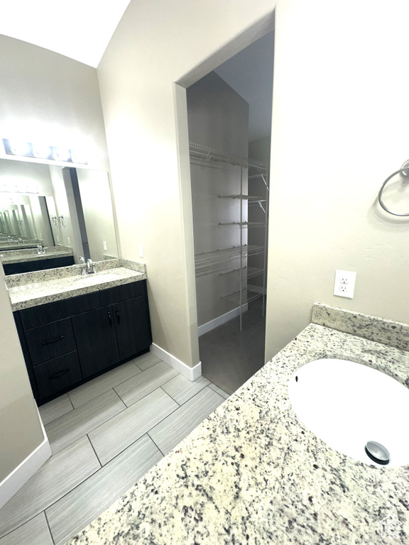 Bathroom with vanity, baseboards, and a spacious closet