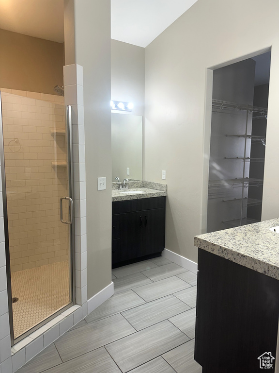 Full bathroom with a stall shower, baseboards, vanity, and a walk in closet