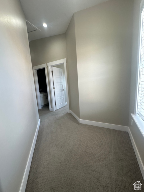 Carpeted empty room featuring baseboards, attic access, and recessed lighting