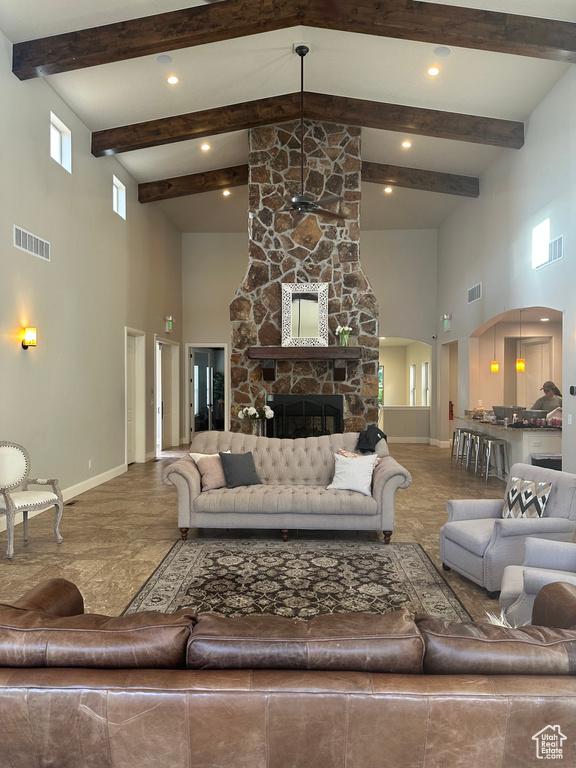 Living room featuring a high ceiling, arched walkways, baseboards, beam ceiling, and a fireplace