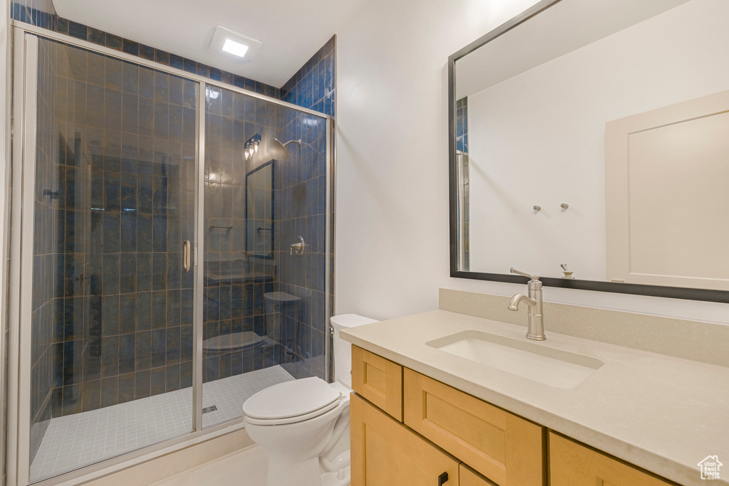 Full bathroom featuring toilet, a stall shower, and vanity