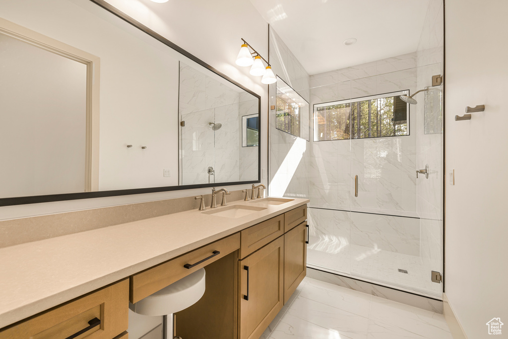 Full bathroom with marble finish flooring, a shower stall, and vanity