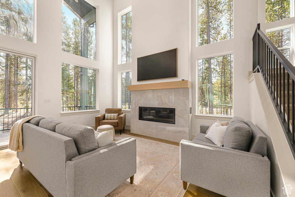 Living area with a towering ceiling, plenty of natural light, a fireplace, and wood finished floors