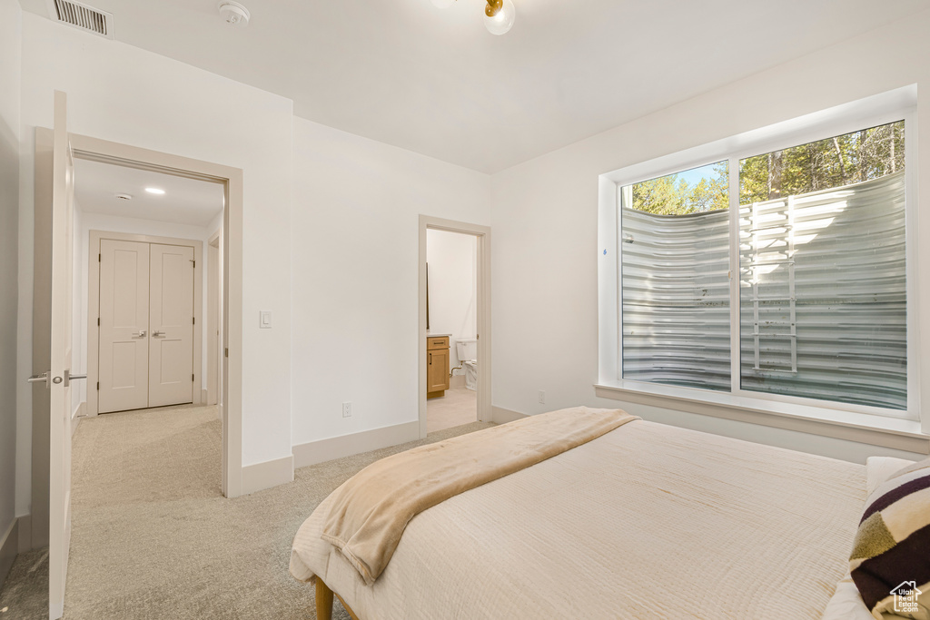 Bedroom with light carpet, baseboards, and ensuite bathroom