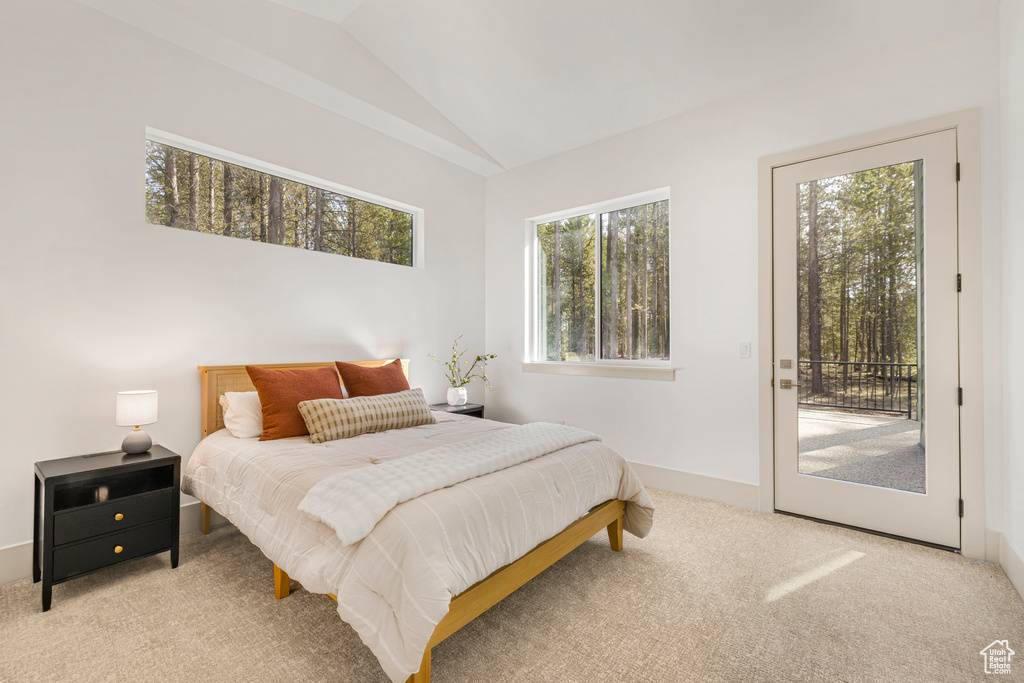 Carpeted bedroom featuring access to exterior, vaulted ceiling, and baseboards