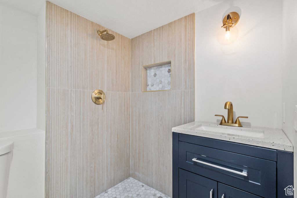Full bath with tiled shower, toilet, and vanity