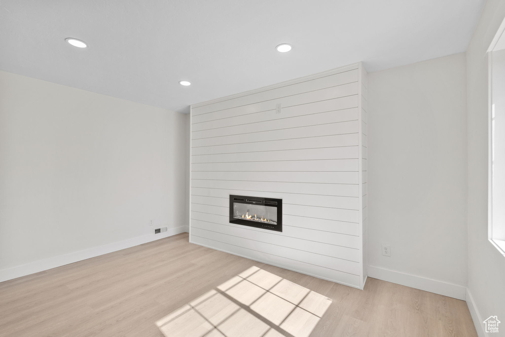Unfurnished living room featuring light wood finished floors, a large fireplace, recessed lighting, and baseboards
