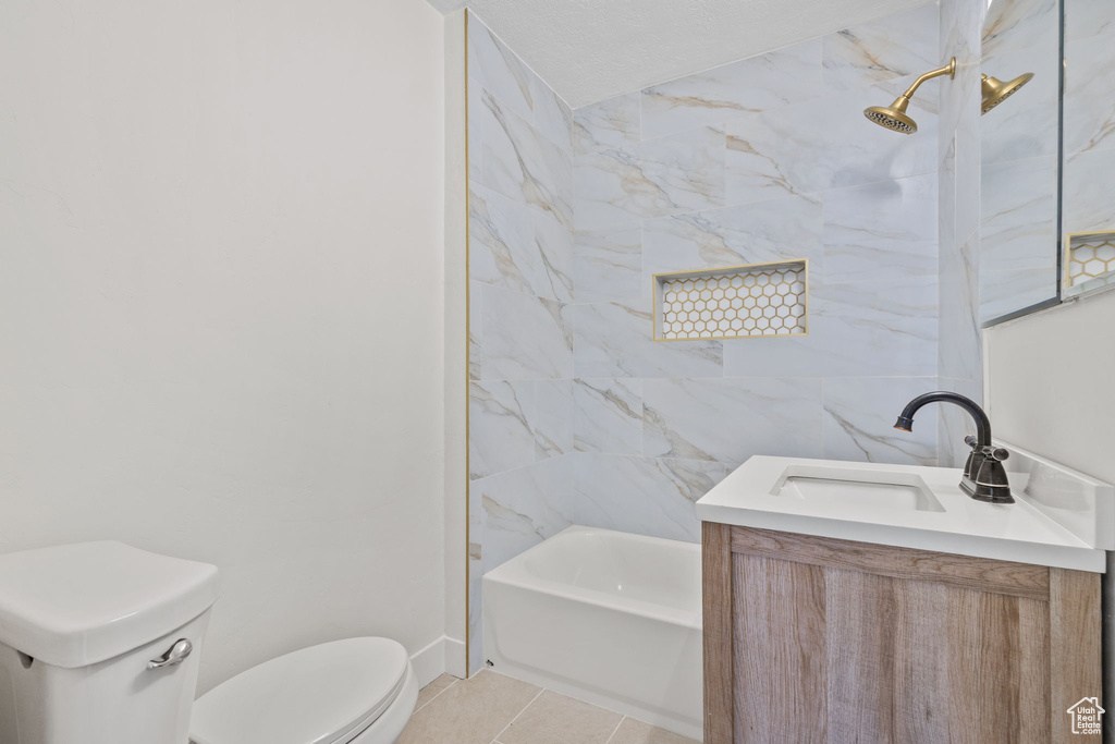 Full bathroom with tile patterned floors, toilet, vanity, baseboards, and tub / shower combination