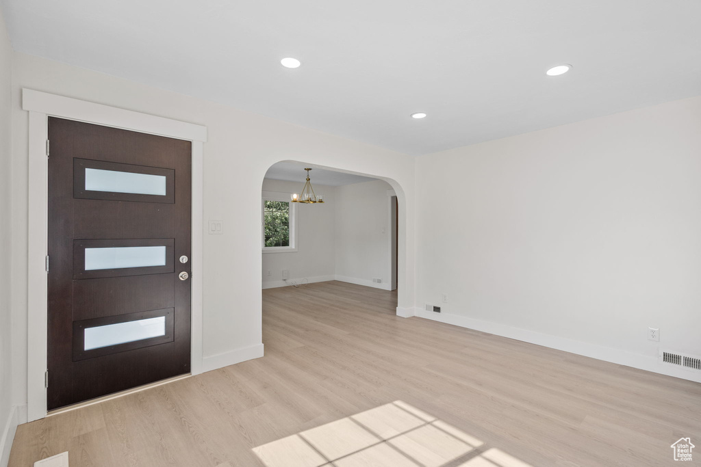 Entrance foyer featuring arched walkways, light wood finished floors, baseboards, a chandelier, and recessed lighting