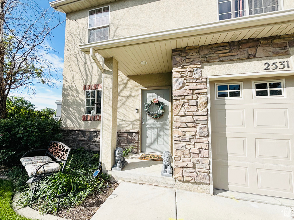 Entrance to property featuring stone siding, stucco siding, and covered porch