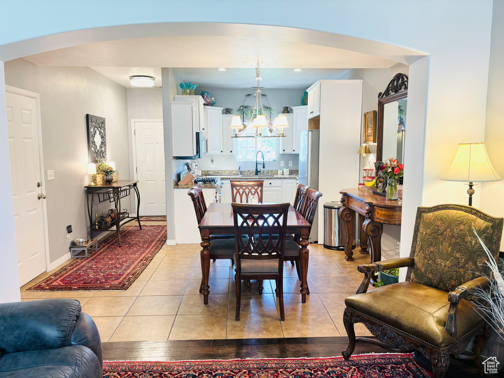 Dining area with arched walkways, a chandelier, and light tile patterned floors