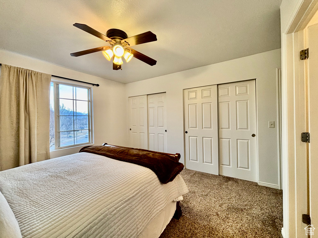 Carpeted bedroom featuring two closets and a ceiling fan