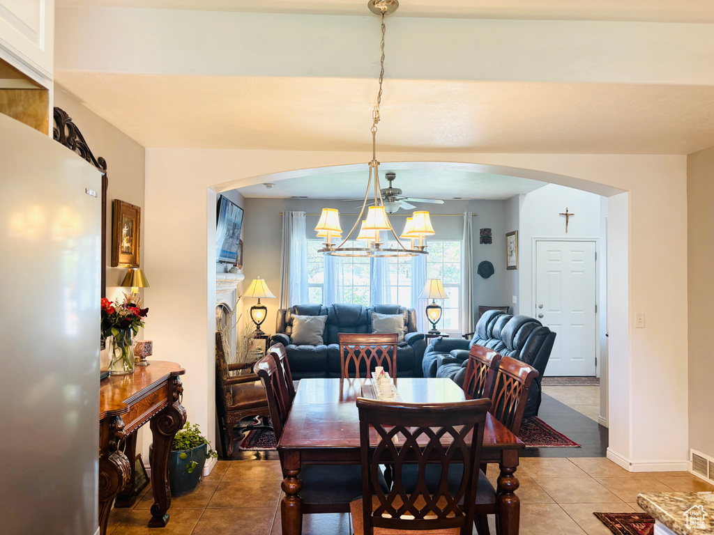 Dining room with arched walkways, light tile patterned flooring, a chandelier, and baseboards