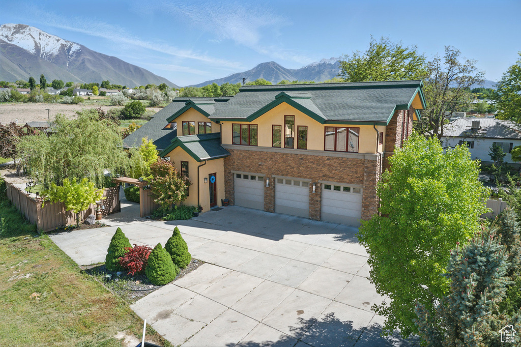 View of front of property featuring stucco siding, a garage, driveway, a mountain view, and stone siding