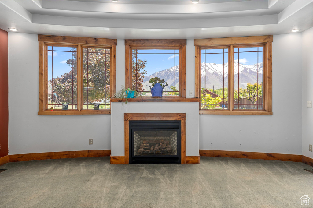 Unfurnished living room featuring carpet flooring, baseboards, a glass covered fireplace, a mountain view, and recessed lighting