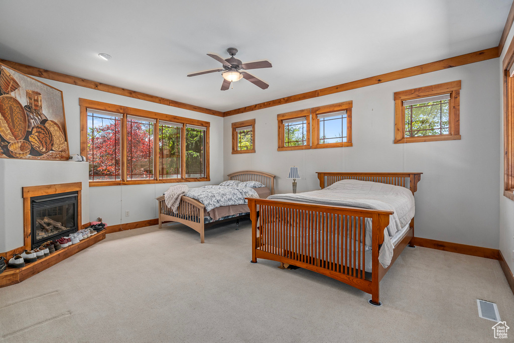 Carpeted bedroom with baseboards, a glass covered fireplace, and ceiling fan