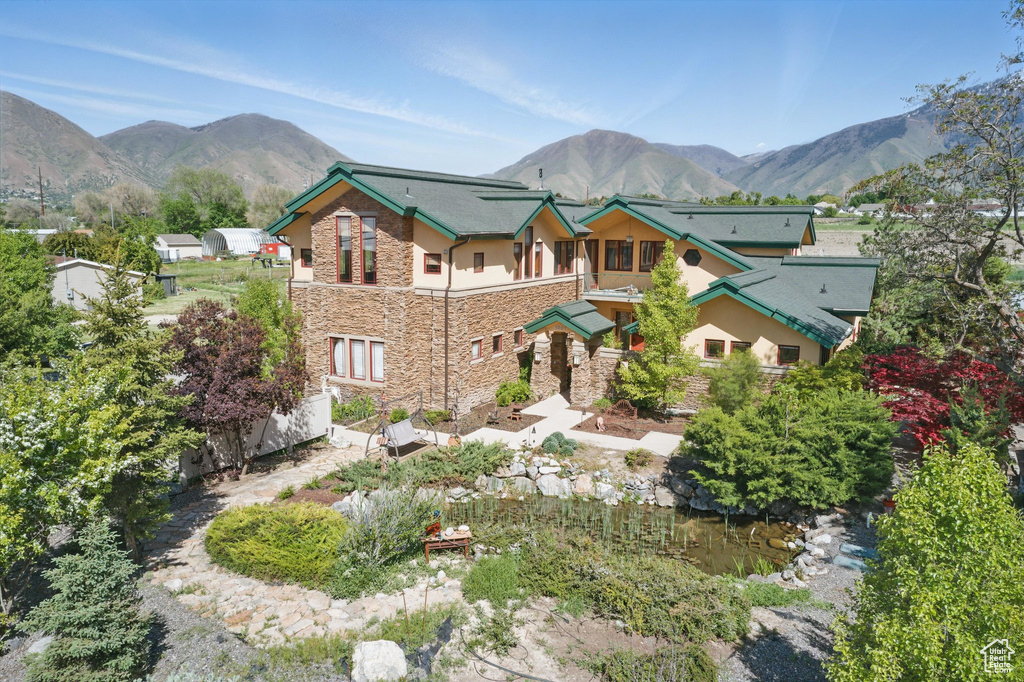 View of front of home featuring stone siding, a mountain view, and stucco siding