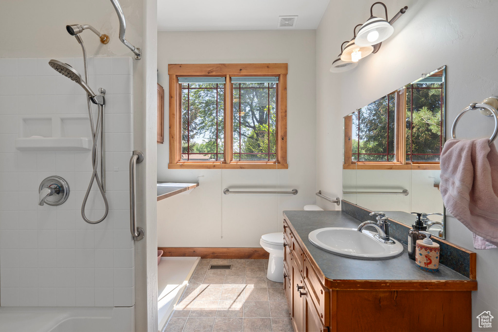 Full bath featuring a shower, vanity, toilet, baseboards, and tile patterned floors
