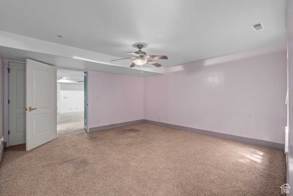 Spare room featuring a ceiling fan, light carpet, and baseboards