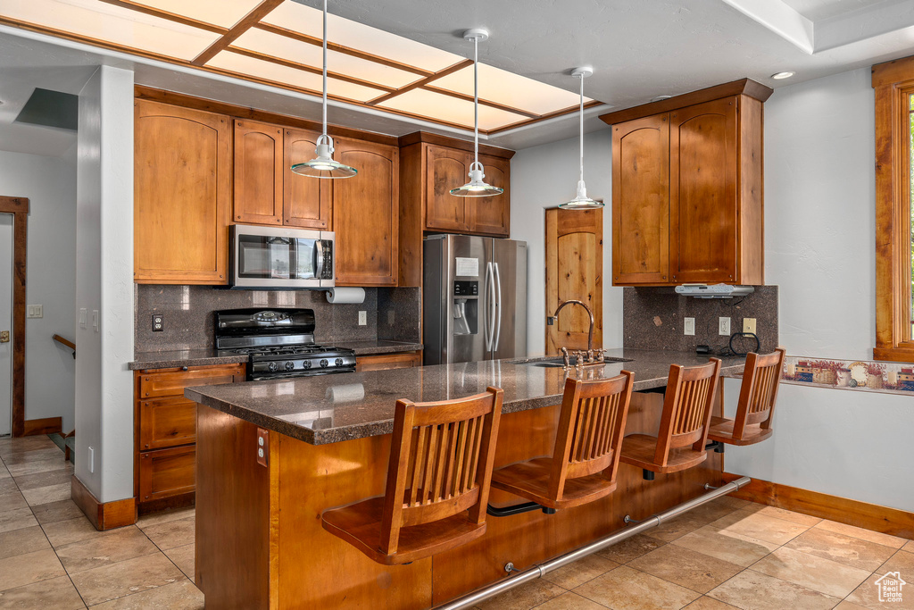 Kitchen with stainless steel appliances, a sink, baseboards, a peninsula, and backsplash