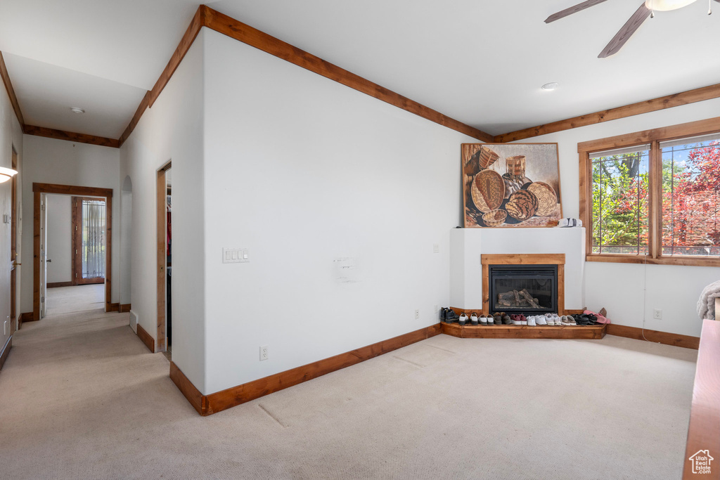 Unfurnished living room with light carpet, a glass covered fireplace, baseboards, and ceiling fan