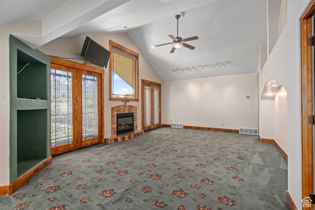 Unfurnished living room with lofted ceiling, carpet floors, ceiling fan, a tile fireplace, and baseboards