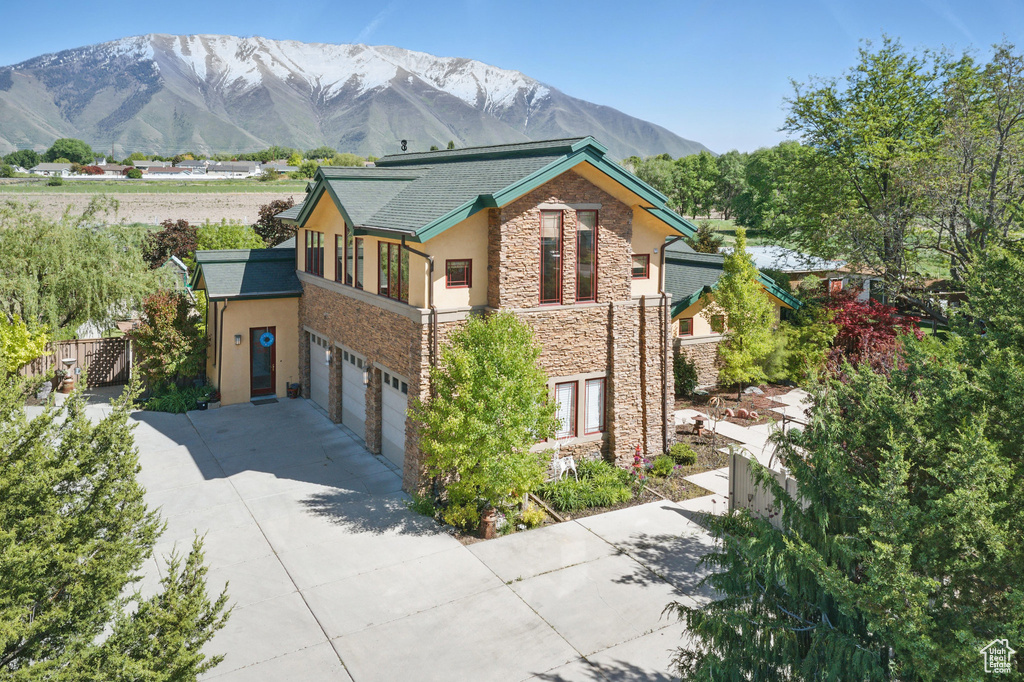 View of side of property with stone siding, stucco siding, a garage, driveway, and a mountain view
