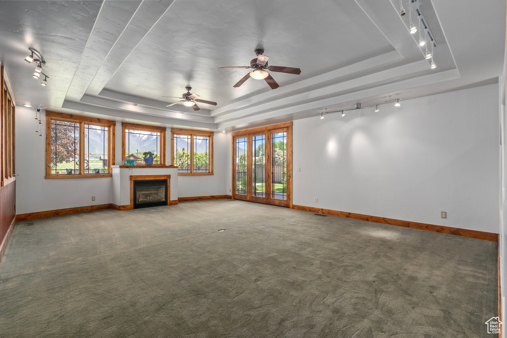 Unfurnished living room with a raised ceiling, baseboards, and carpet floors