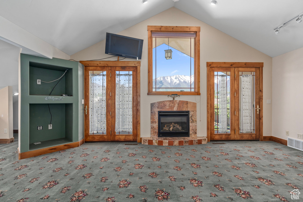 Unfurnished living room featuring vaulted ceiling, carpet flooring, a tile fireplace, and baseboards