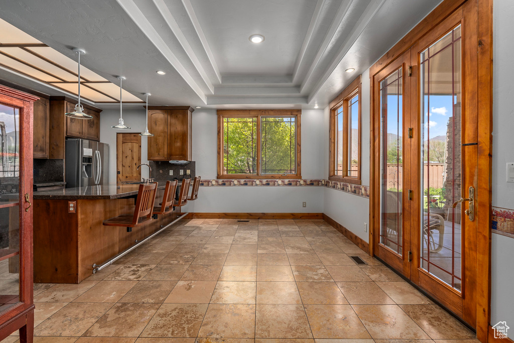 Kitchen with stainless steel fridge, a tray ceiling, tasteful backsplash, baseboards, and a sink