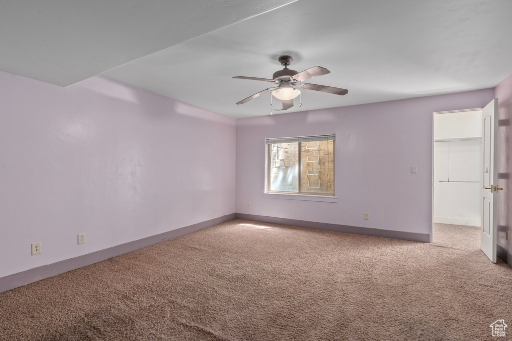 Spare room with carpet floors, a ceiling fan, and baseboards
