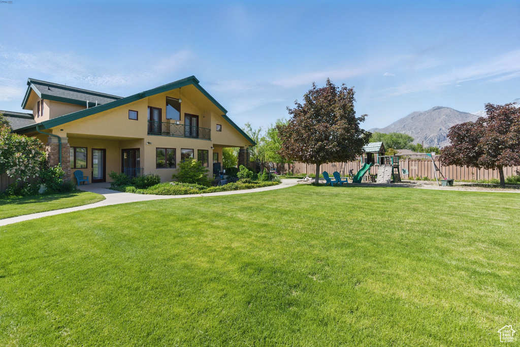 View of front of home featuring a mountain view, stucco siding, and a balcony