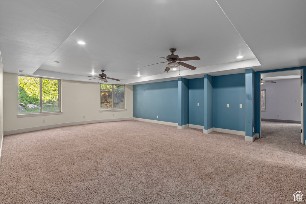Carpeted empty room with a ceiling fan, baseboards, recessed lighting, and a raised ceiling