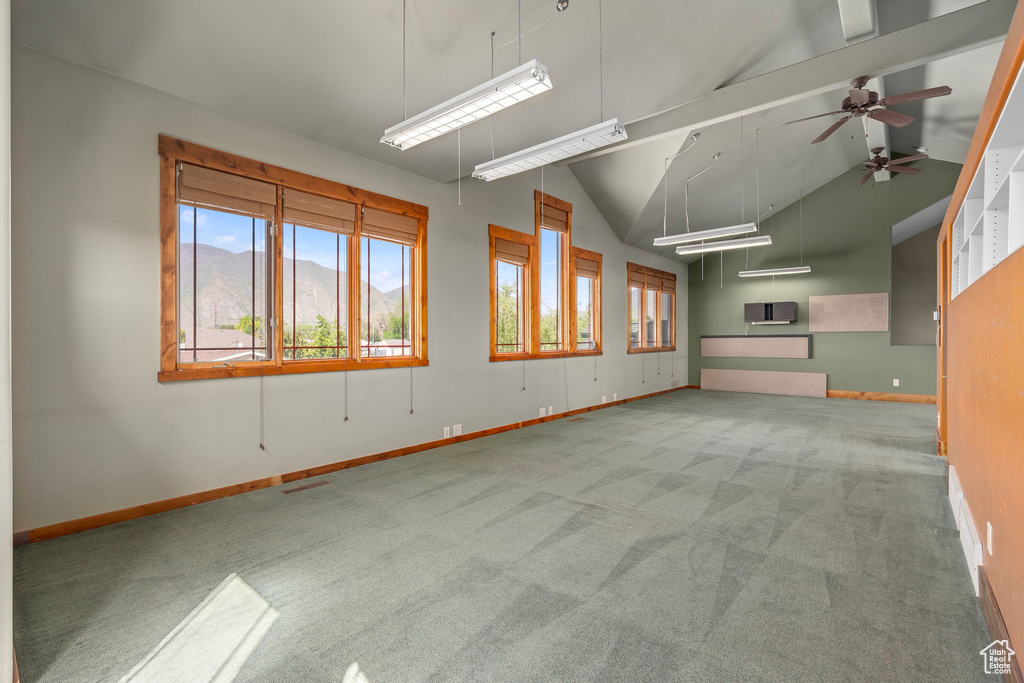 Empty room featuring carpet floors, baseboards, and high vaulted ceiling