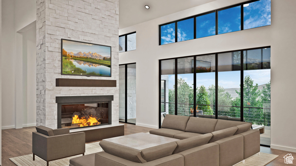 Living room with baseboards, a towering ceiling, a fireplace, and wood finished floors