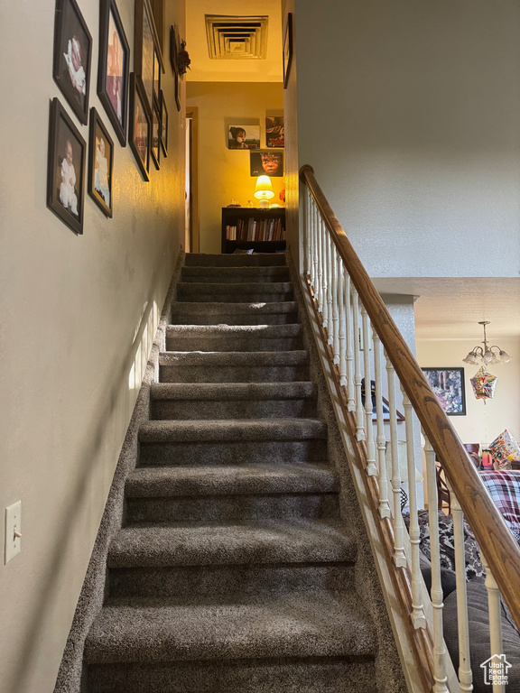 Staircase featuring a high ceiling and a chandelier