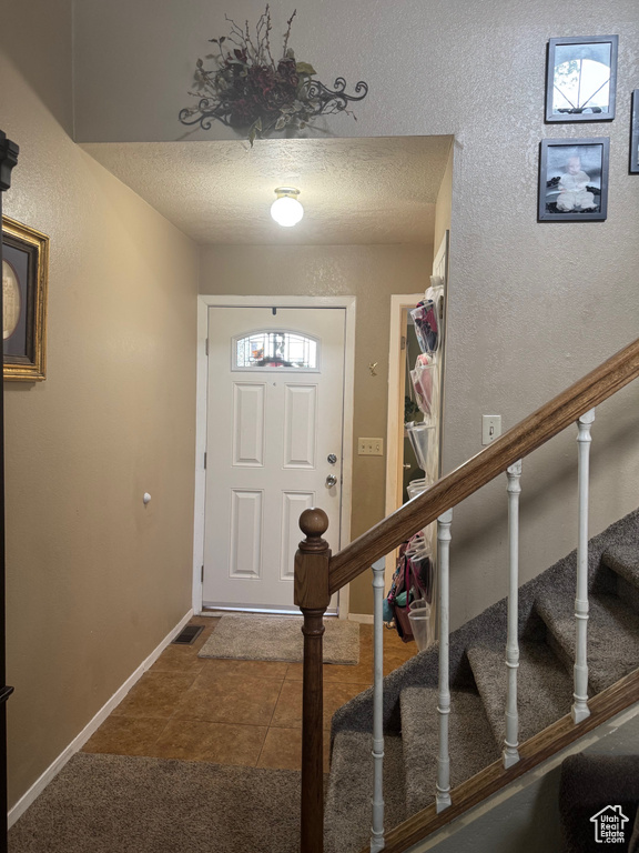 Entrance foyer featuring stairway, a textured ceiling, baseboards, and tile patterned floors