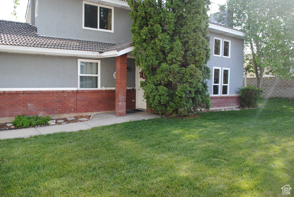 View of front of home featuring brick siding, stucco siding, and a tiled roof