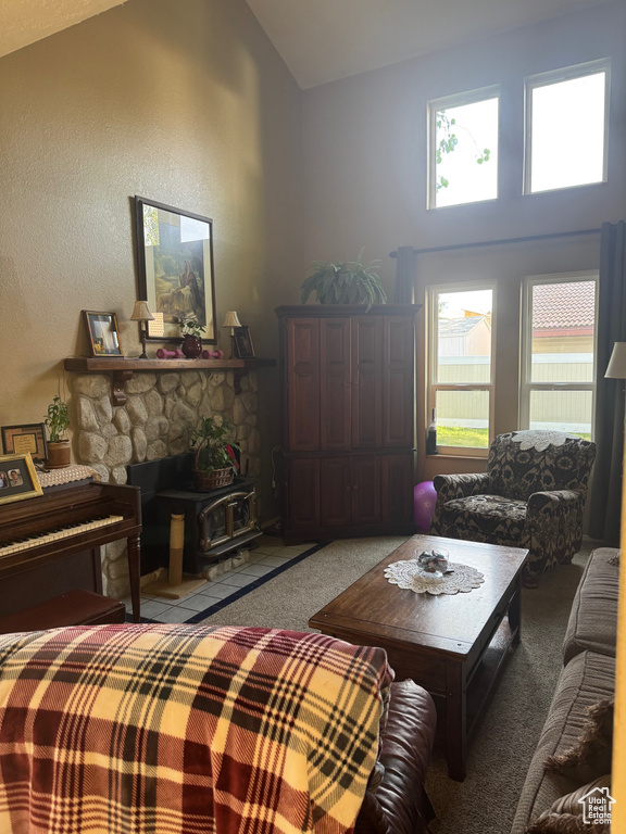 Carpeted living area featuring vaulted ceiling and a wood stove